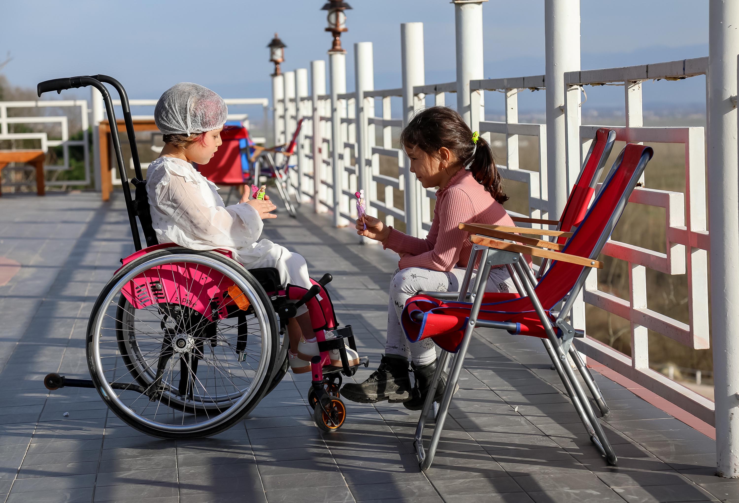 two girls one in wheel chair and other in regular chair
